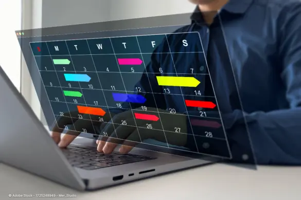 Eine Person arbeitet am Laptop mit eingeblendetem digitalen Terminkalender und farbigen Aufgabenbalken, um die Arbeitsorganisation verbessern zu können.